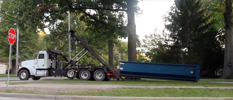 Roll-off dumpster delivery truck placing a container in New Braunfels, TX