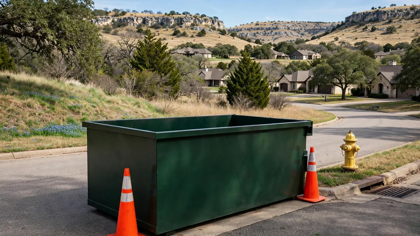 Roll-off dumpster placed at a residential curb with traffic cones